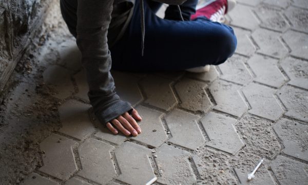 substance abuse, addiction, people and drug use concept - close up of addict woman and used syringes on ground