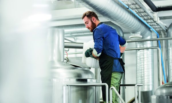 manufacture, business and people concept - man working at craft brewery or beer plant