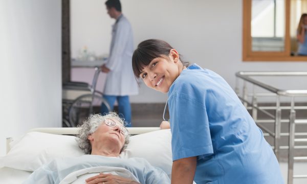 3598547-smiling-nurse-leaning-on-the-bed-of-a-patient